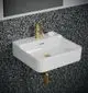 Waschtisch in Weiß mit goldener Armatur und Push-Open-Mechanismus. An der Wand mit Terrazzo-Muster verziert. Ideal Standard Design.